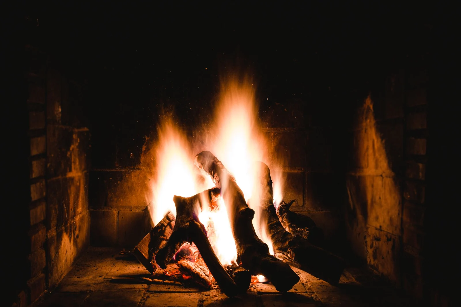 Burning logs and orange flames inside a dark firebox