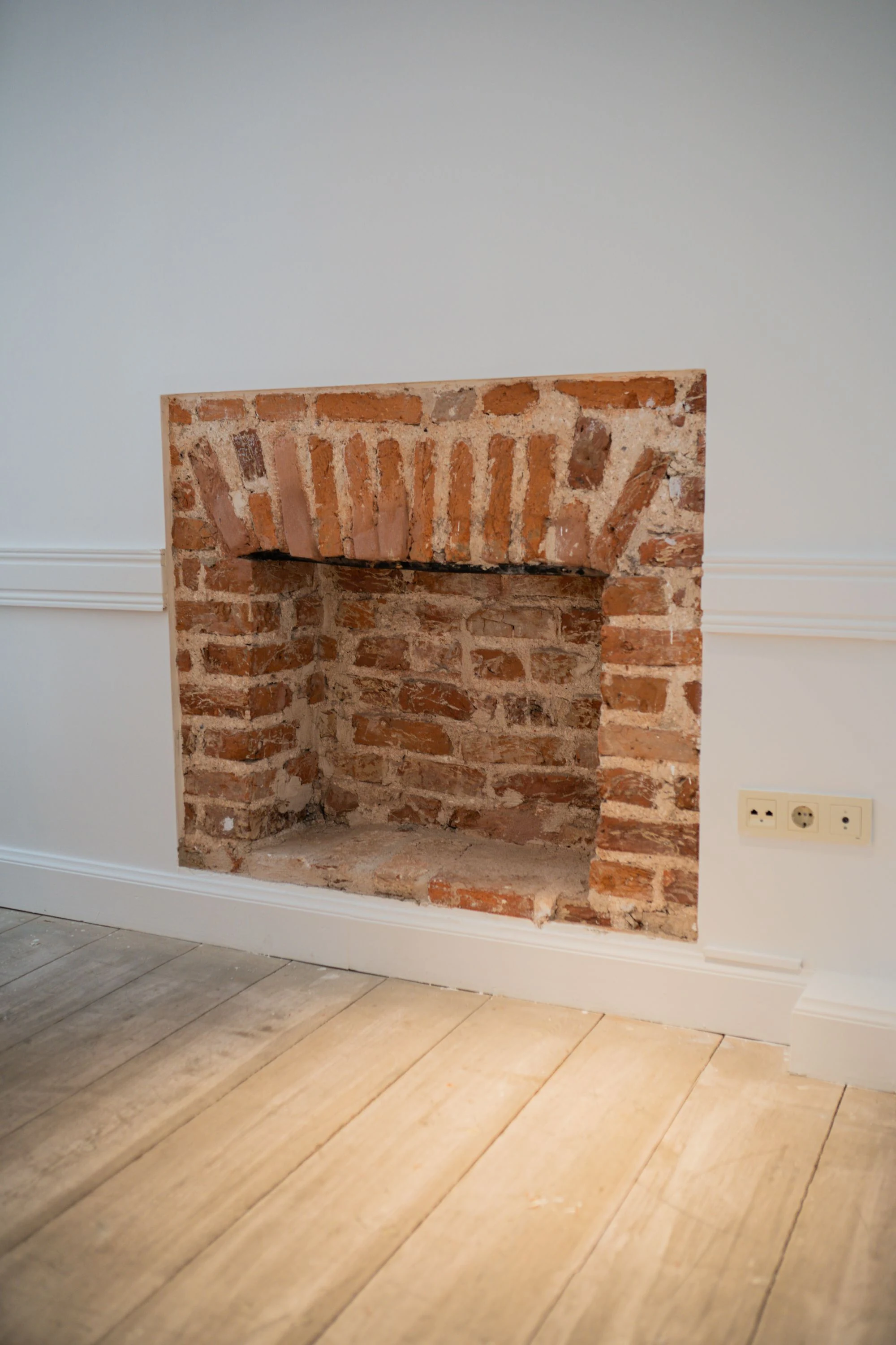 Exposed brickwork inside an unlit fireplace opening